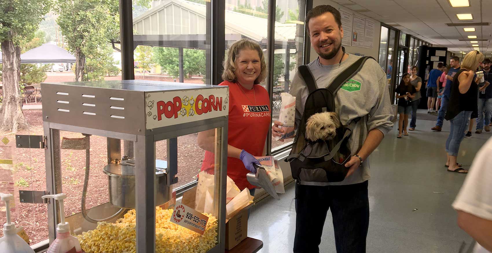 Man and woman standing at popcorn maker with dog
