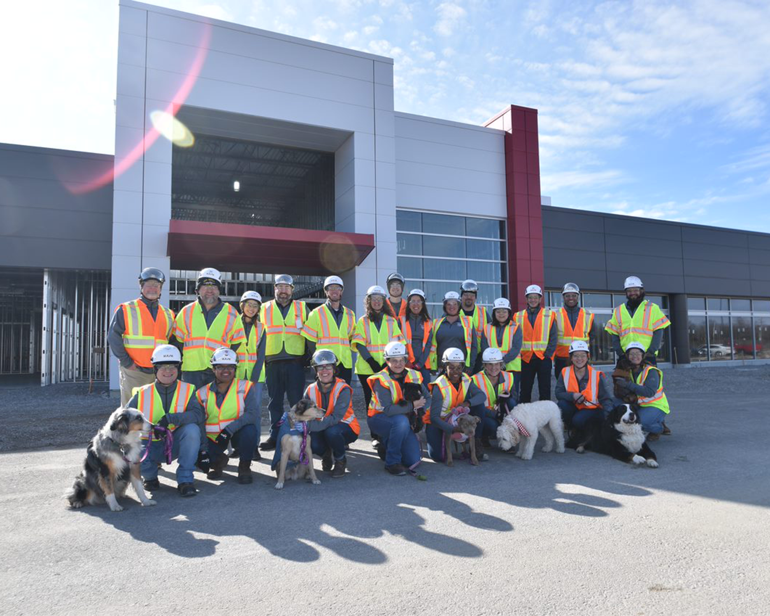 Factory associates and pets standing outside of new facility