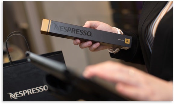 Female holding a pack of Nespresso pods