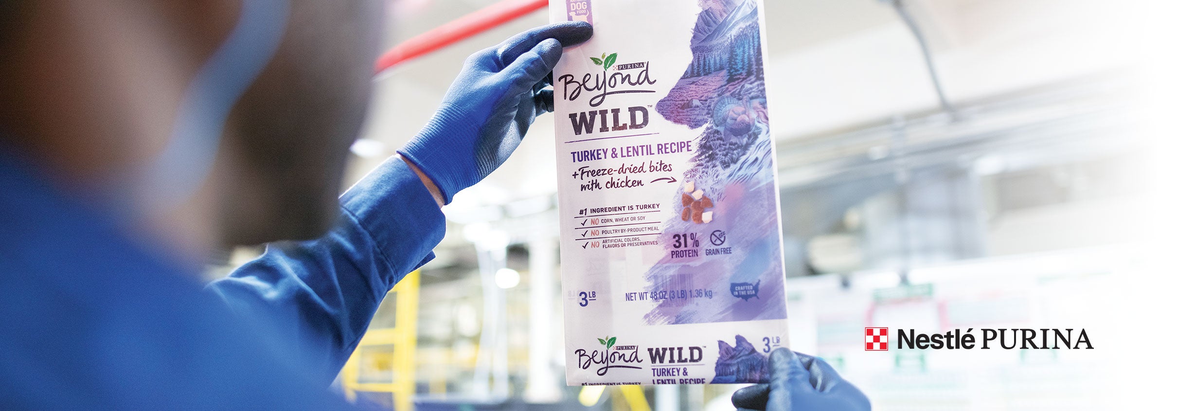 Over the shoulder view of a Purina factory worker inspecting a bag of Beyond