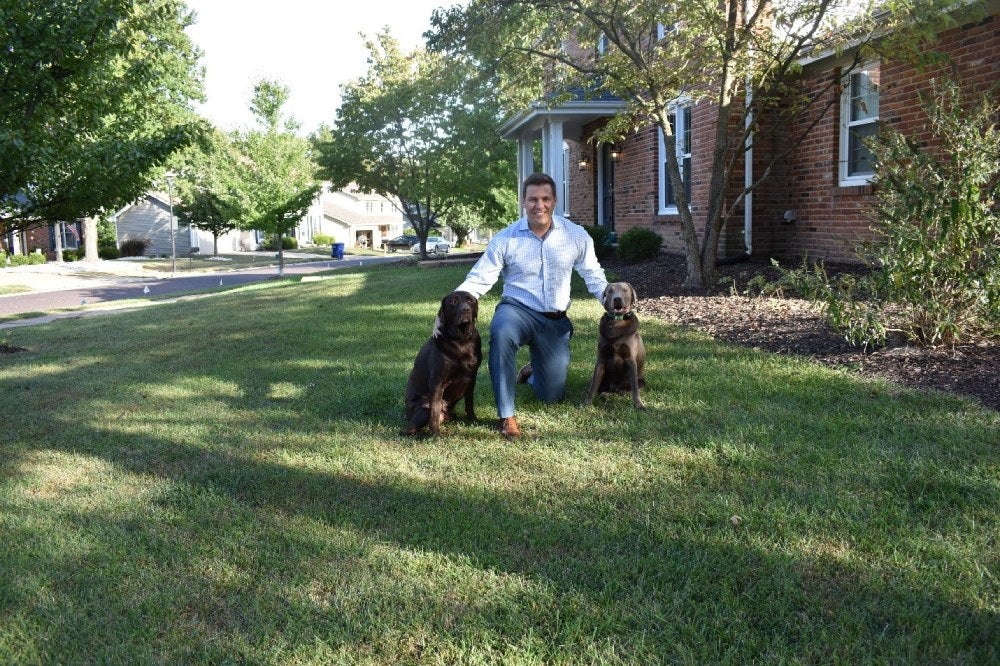 A man with his two dogs in the garden of a house
