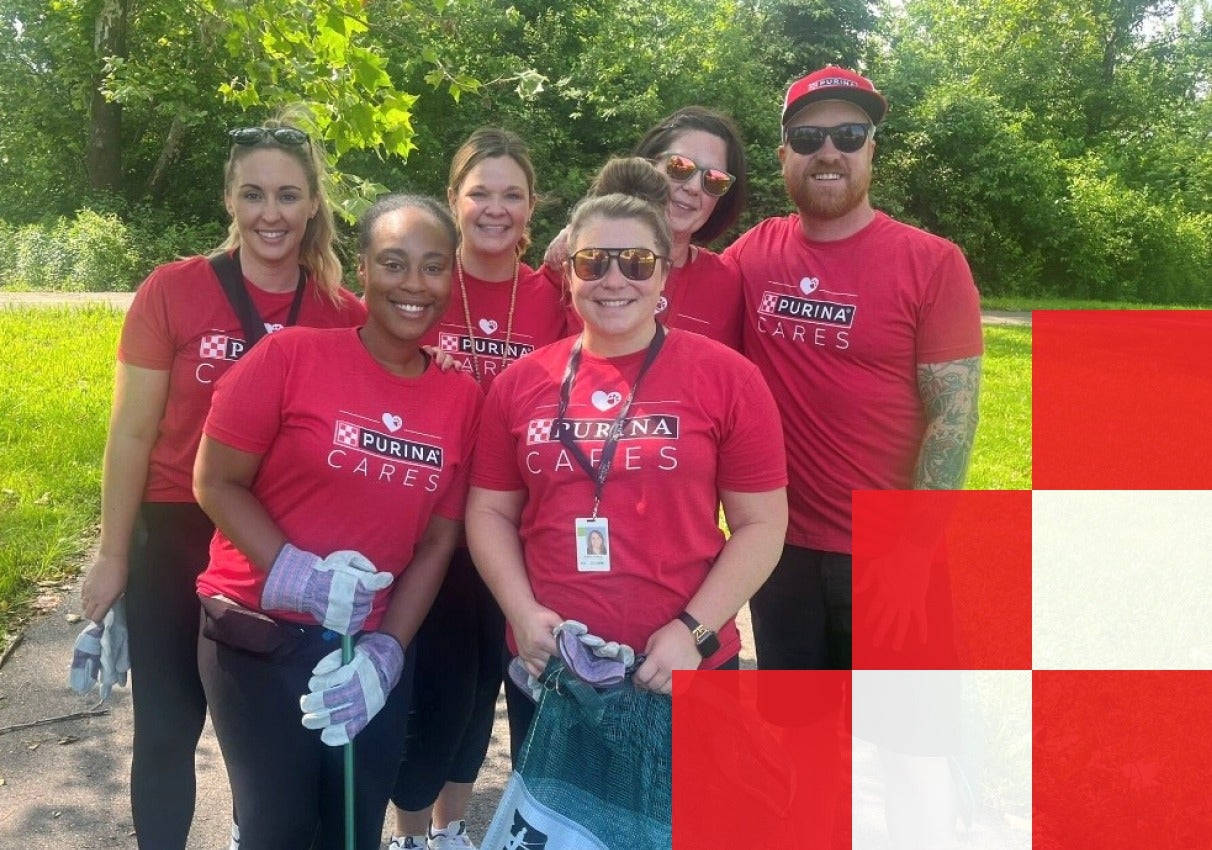 A group of individuals wearing Purina Cares shirts smiles together for a group photo.