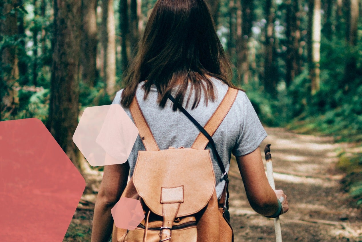 Woman walking in forest with backpack.