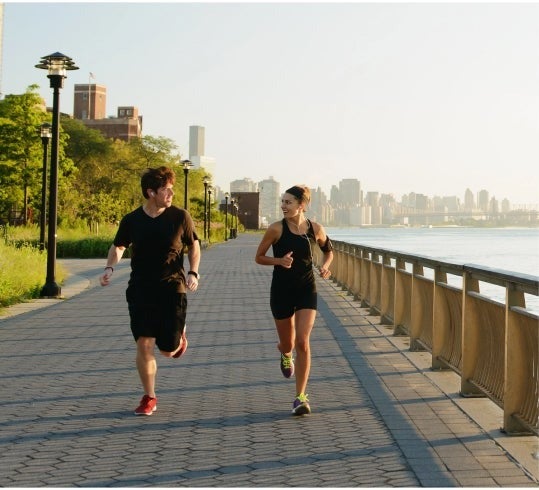 Man and woman running along a body of water