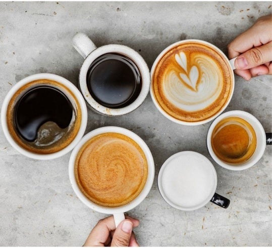 Hands grabbing cups of coffee from table top