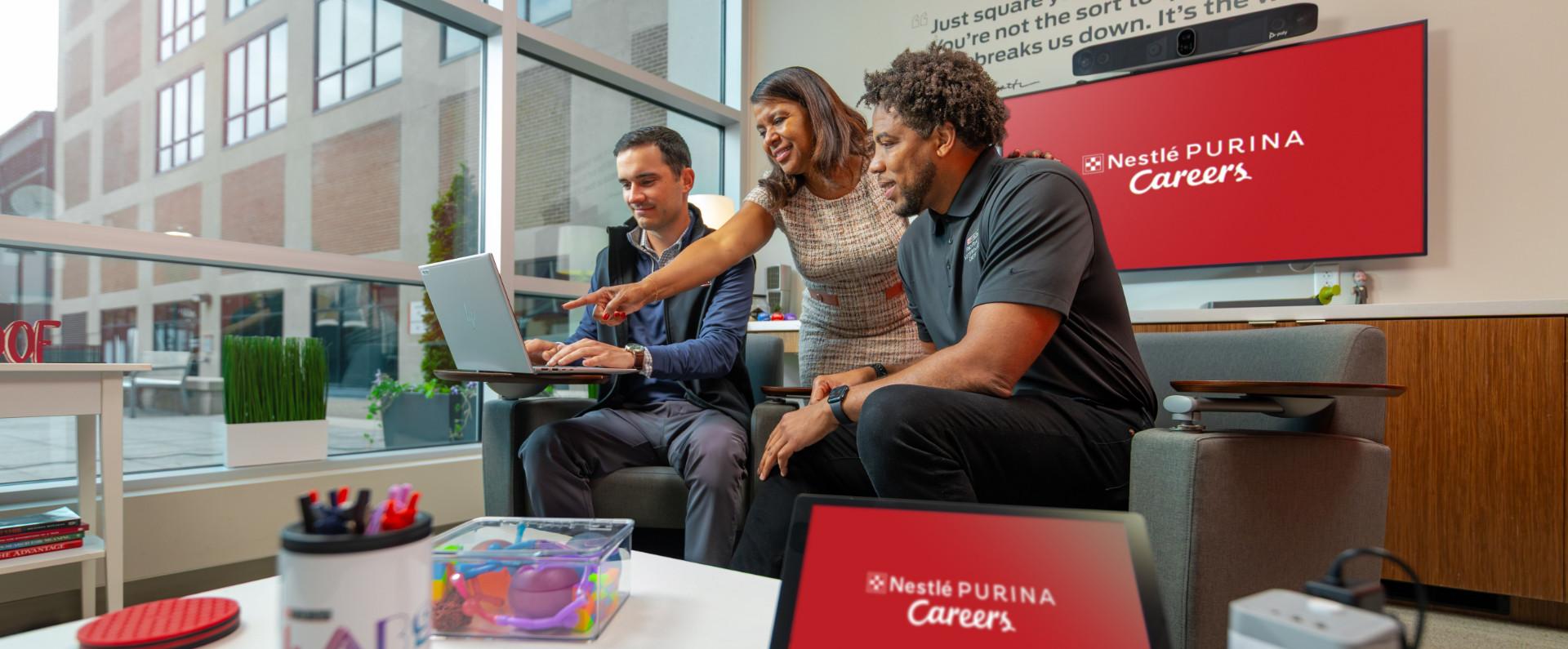 Two men and a woman engaged in conversation over a computer screen